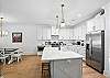 This wide kitchen shot shows the full setup—stone countertops, pendant lighting, and bar seating for quick breakfasts before beach runs.

