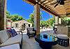 40' long white rock Cabana with round wicker sofa in lounge area next to the bar overlooking the waterfall pool.