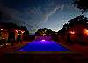 A colored pool light below a sensational night sky.