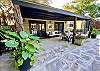 Buck a Roo has flagstone covered patio with rattan sofa & matching chair with white cushions & tropical flowers.