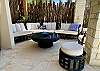 Huge circular rattan sofa, chair & ottoman with white deep cushions and wicker cocktail table.