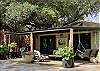 Morning sunshine across the covered flagstone patio w/ upscale outdoor furniture & tropical flowers.