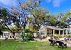 Stunning landscaping of mature trees, palm trees and lush lawn.