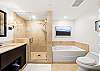 A second angle confirms the primary suite’s separate shower and bathtub, double-vanity layout, toilet, and tiled finishes, giving extended-stay guests a complete en-suite bathroom with room for shared routines.