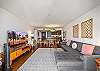 This wide living-room angle brings the sectional, large television, dining table, and open kitchen into one frame, illustrating a comfortable central space for everyday routines and relaxed evenings during a monthly stay.