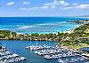 This elevated view layers sailboats in Ala Wai Boat Harbor, the green spaces of Magic Island, Ala Moana Beach Park, and the Pacific Ocean. Capturing this standout coastal setting.