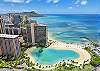 This neighborhood image features nearby Duke Kahanamoku Lagoon, its curved sandy beach, palm-lined shore, and the Pacific Ocean beyond—an off-property Waikiki destination near The Watermark for an extended stay.