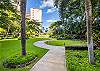 A curved path crosses The Watermark Waikiki’s landscaped lawn, framed by palms and tropical plantings—an appealing garden setting within the residential grounds for guests enjoying an extended Honolulu stay.