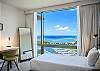Positioned beside the guest bedroom’s desk and twin bed, the floor-to-ceiling window frames Ala Wai Boat Harbor and Pacific Ocean views, bringing a strong sense of place to work, read, or unwind during a monthly stay.