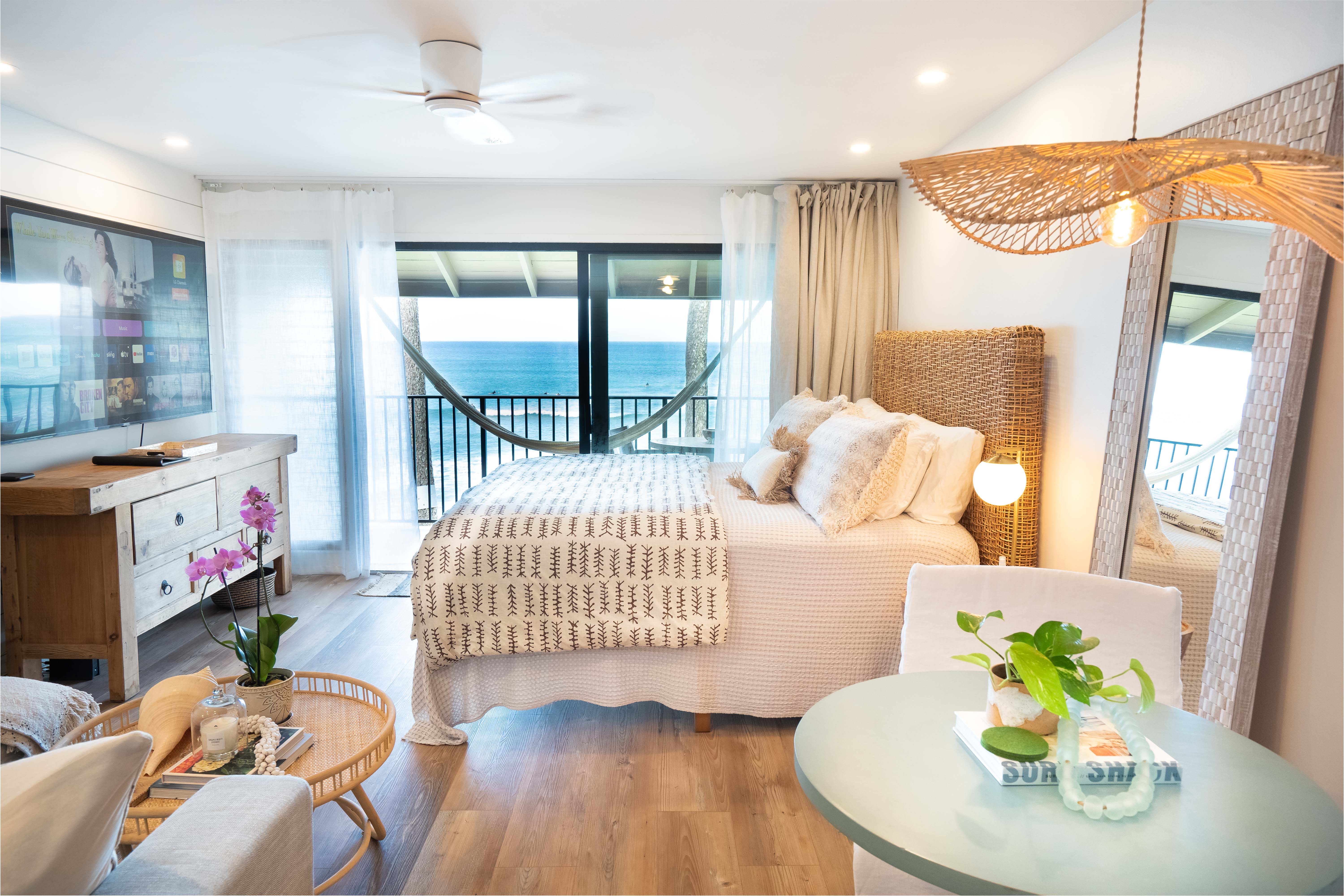 Modern, newly remodeled studio at Noelani 219 featuring a king-size bed, large flat-screen TV, and panoramic ocean views through floor-to-ceiling windows in Kahana, Maui.