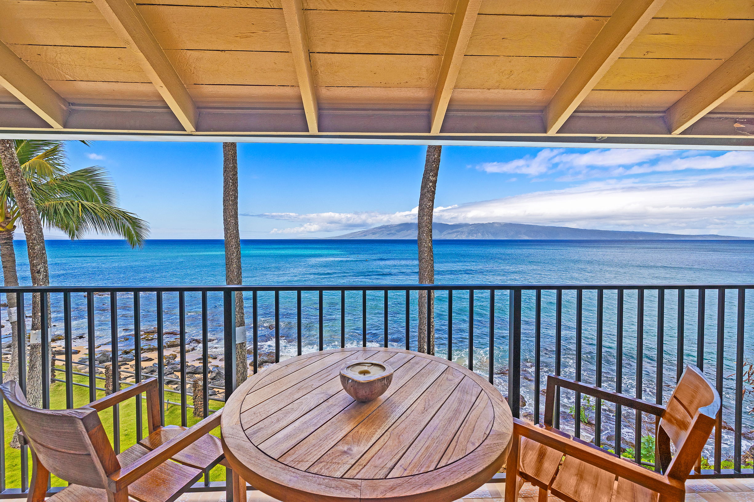 Private lanai at Noelani 219 with high-top table and chairs, showcasing breathtaking ocean views of Moloka'i and Lanai, perfect for whale watching and Maui sunsets.