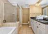 Huge master bathroom has jetted tub and separate glass enclosed shower.