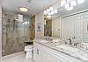 Guest bathroom with double vanity, large walk-in shower and a closet that houses the washer and dryer.  