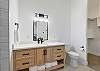 This bathroom includes a walk-in shower, toilet, large vanity, and walk-in closet.