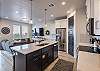 Side view of kitchen showing off the beautiful counter tops and stainless-steel appliances. 