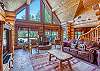 Cozy log cabin living room with vaulted ceilings, large windows, rustic wood accents, and a stone fireplace for the perfect mountain retreat feel
