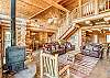Warm and inviting log cabin interior with leather seating, rustic wood finishes, a cozy stove, and an open loft design