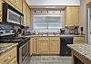 The large, open kitchen features stainless appliances, which include a dishwasher, electric oven, built in microwave, and refrigerator with ice maker.