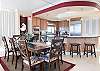 The open dining area features a table with seating for 8 with additional seats offered at the adjacent bar.