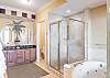 The private bathroom included with the primary suite, features a spa-like jacuzzi tub, glass shower, double vanities, and is fully stocked with linens for your stay.