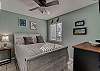 Bedroom 1 offers new queen bedding, a bedside table with lamp, a dresser and a mounted flat screen television