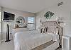 The bedroom offers queen bedding, chest of drawers and a mounted flat screen television
