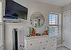 The bedroom offers a dresser and a mounted flat screen television