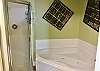 The large, private bathroom offers a standing shower and a jetted soaking tub