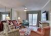 The living area offers a sofa, 3 additional chairs for extra seating, end tables with lamps, a wall mounted flat screen television and stand.