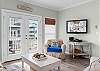 The open living area features a mounted television and plenty of comfortable seating, offering the perfect space for you to relax and unwind after a long day at the beach.