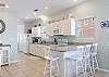 The open and spacious kitchen features white appliances and is fully stocked with all items needed for meal prepping. A bar is offered with seating for 4 and provides extra space for mealtime.