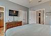 The primary bedroom offers a large dresser and a mounted television. A spacious closet is included for storing your personal belongings out of the way