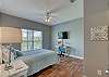 Guest Bedroom 1 offers queen bedding, bedside tables with lamps, a small desk and a mounted television.