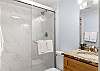A private bathroom is featured with the primary bedroom and offers a tiled shower, single vanity, and is fully stocked with linens for your stay.