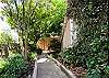 The home is nestled in jasmine and bottle brush trees. This walk way leads to the stairs that go up to the home entrance. It's like walking up to a tree house!