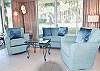 Cozy lobby seating area with modern furnishings and peaceful garden views through floor-to-ceiling windows.