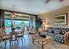 Bright living and dining area with large sliding doors opening to a spacious lanai and views across the Maui Eldorado grounds toward the ocean.