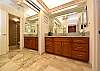Large bathroom with granite double-sink vanity, mirrored closets, and warm modern finishes.