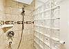Glass-enclosed tile shower with upgraded fixtures.