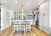 Stunning remodeled kitchen featuring quartz counters, custom backsplash, stainless appliances, and island seating for three.