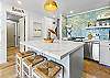 Beautiful oversized island with quartz surfaces, bar seating, and a view into the fully updated coastal-style kitchen.
