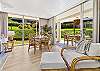 Spacious living and dining area with floor-to-ceiling windows opening to a lush garden-level lanai.