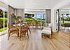 Open, sun-filled dining space with floor-to-ceiling windows showcasing the lush landscaped grounds.