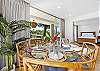 Beautiful dining setup with views into the bedroom and direct access to the lanai overlooking lush greenery.