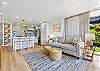 Bright, fully remodeled living area with stylish furnishings and an open kitchen featuring bar seating.