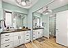 Well-appointed bathroom featuring a double-sink vanity, modern lighting, and a separate walk-in shower for added comfort.