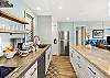 Sleek galley kitchen featuring stainless steel appliances, open shelving, and ample counter space flowing into the living area.