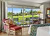 Comfortable bedroom seating area with sliding glass doors opening to the lanai and peaceful garden and golf course views.