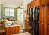 Kitchen with large pantry and three-door refrigerator and freezer looking toward breakfast nook and den