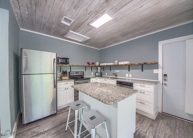 Step up a level from the living room, and find the full kitchen! Two tables seat a total of 10, with two more spots at the breakfast bar. The kitchen comes stocked with cookware, dishes, and utensils.